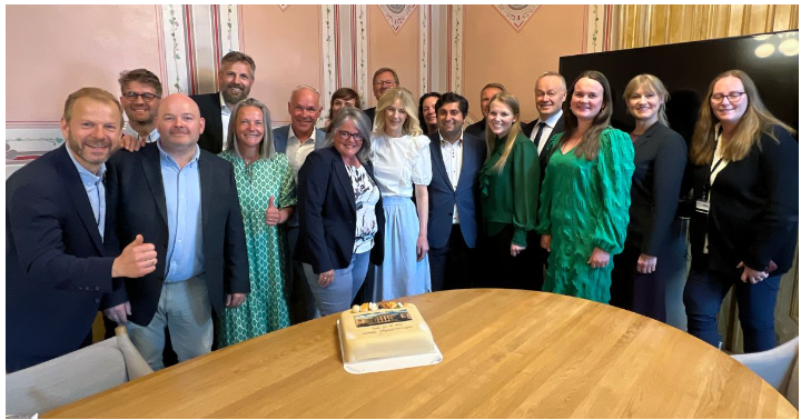 Smilende mennesker med kake på stortinget